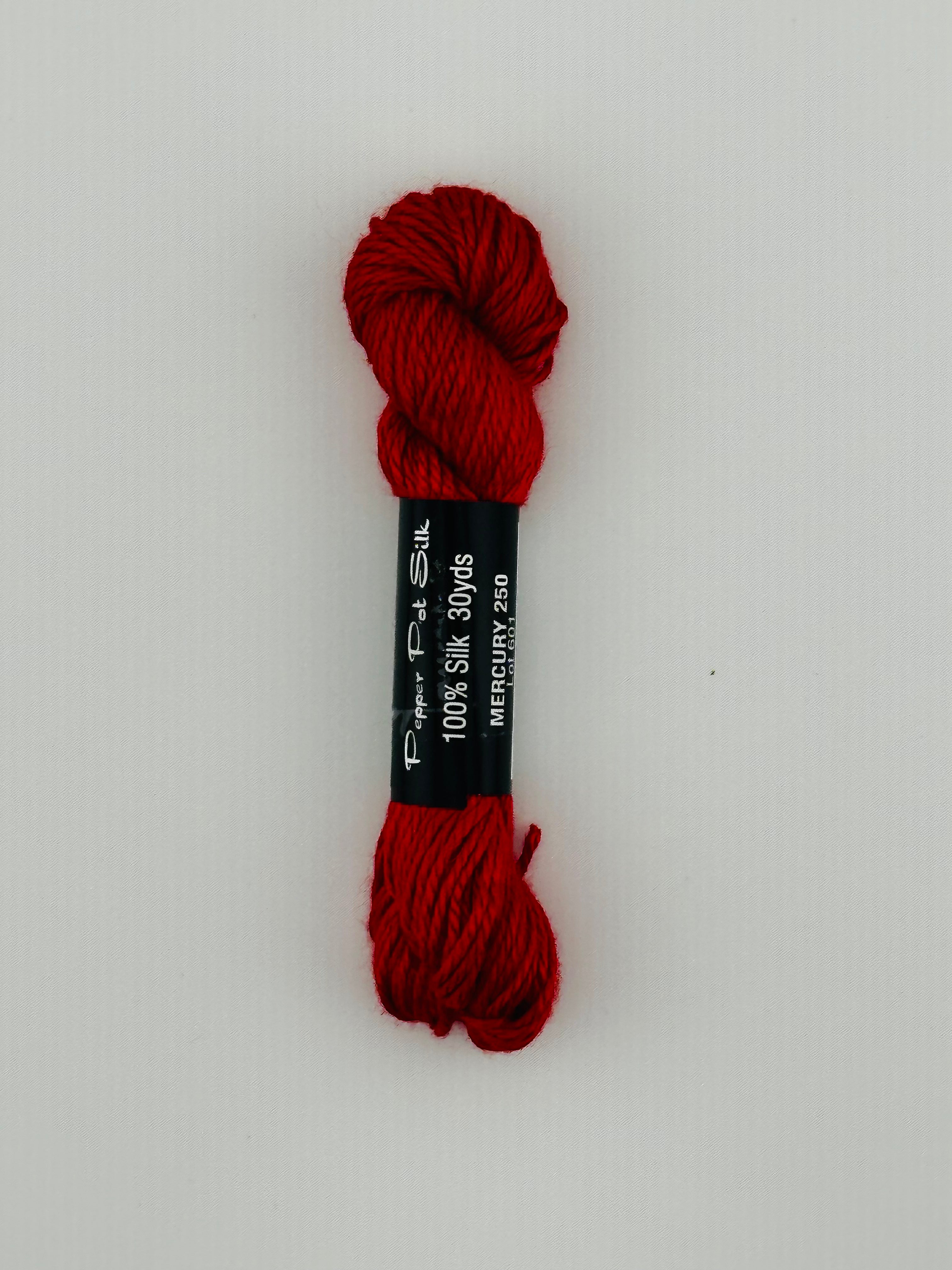 30 yard skein of Pepper Pot Silk needlepoint thread in mercury 250, with black and white label lying flat on white background