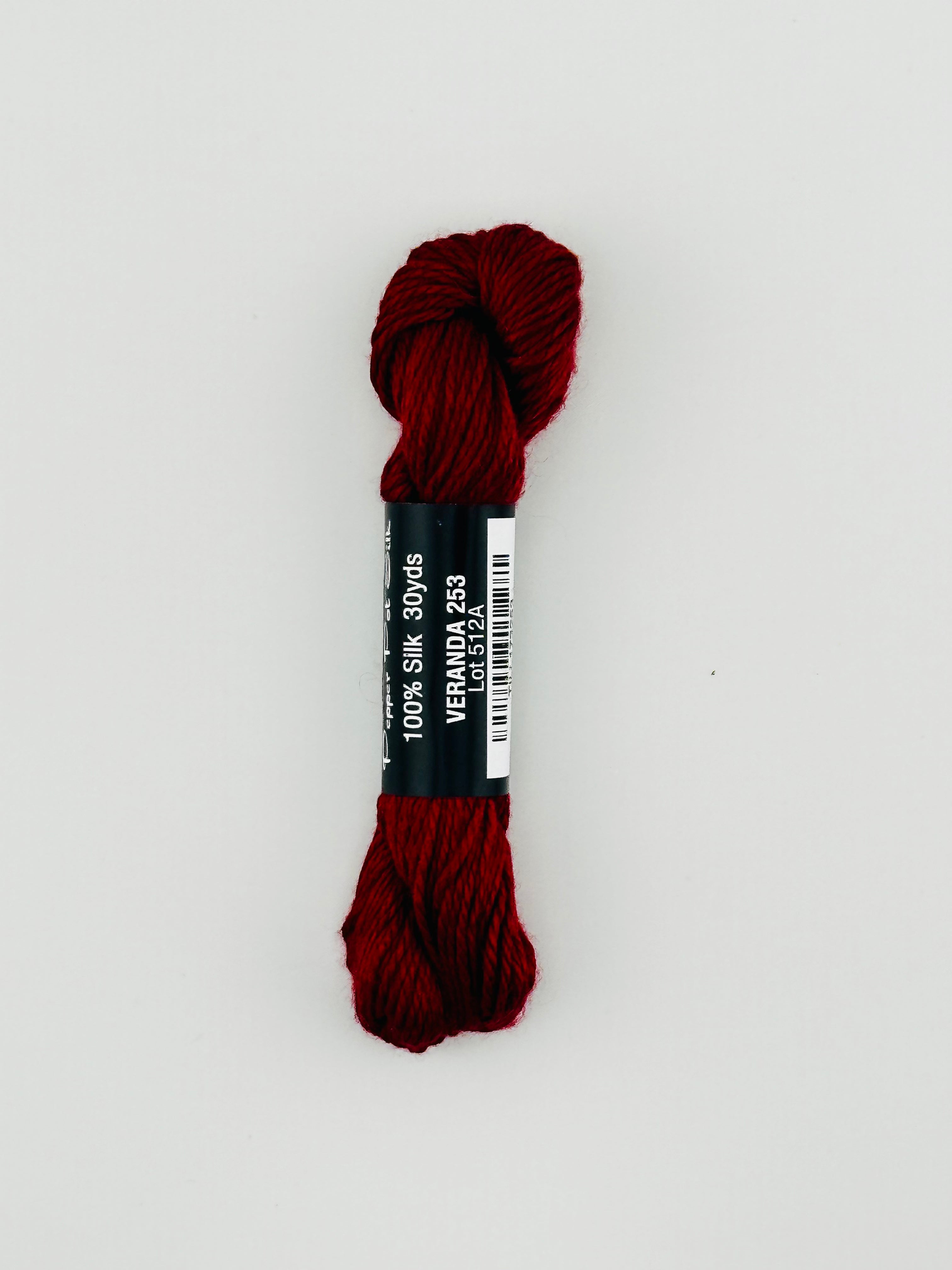 30 yard skein of Pepper Pot Silk needlepoint thread in veranda 253 with black and white label lying flat on white background