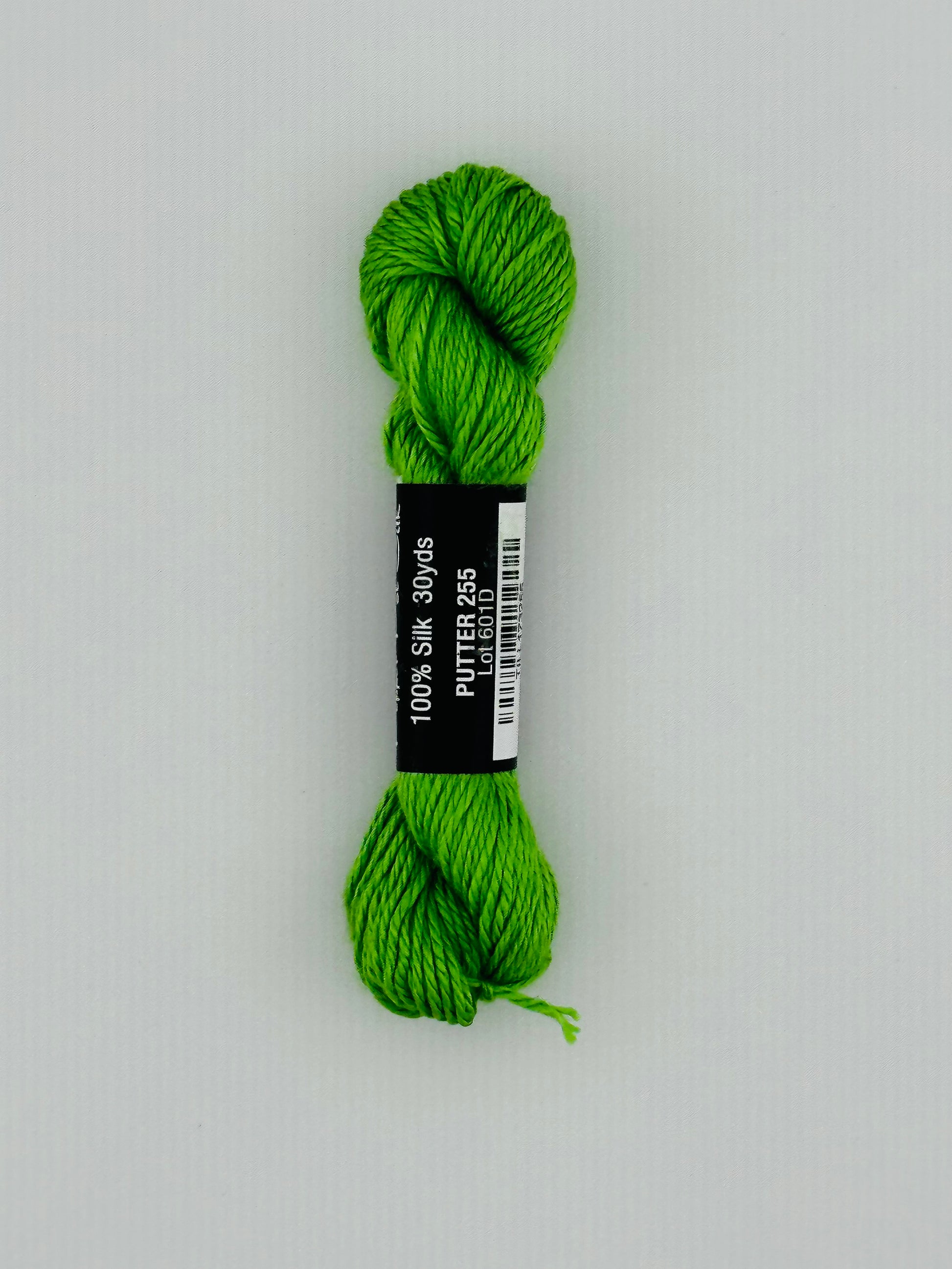 30 yard skein of Pepper Pot Silk needlepoint thread in putter 255, with black and white label lying flat on white background