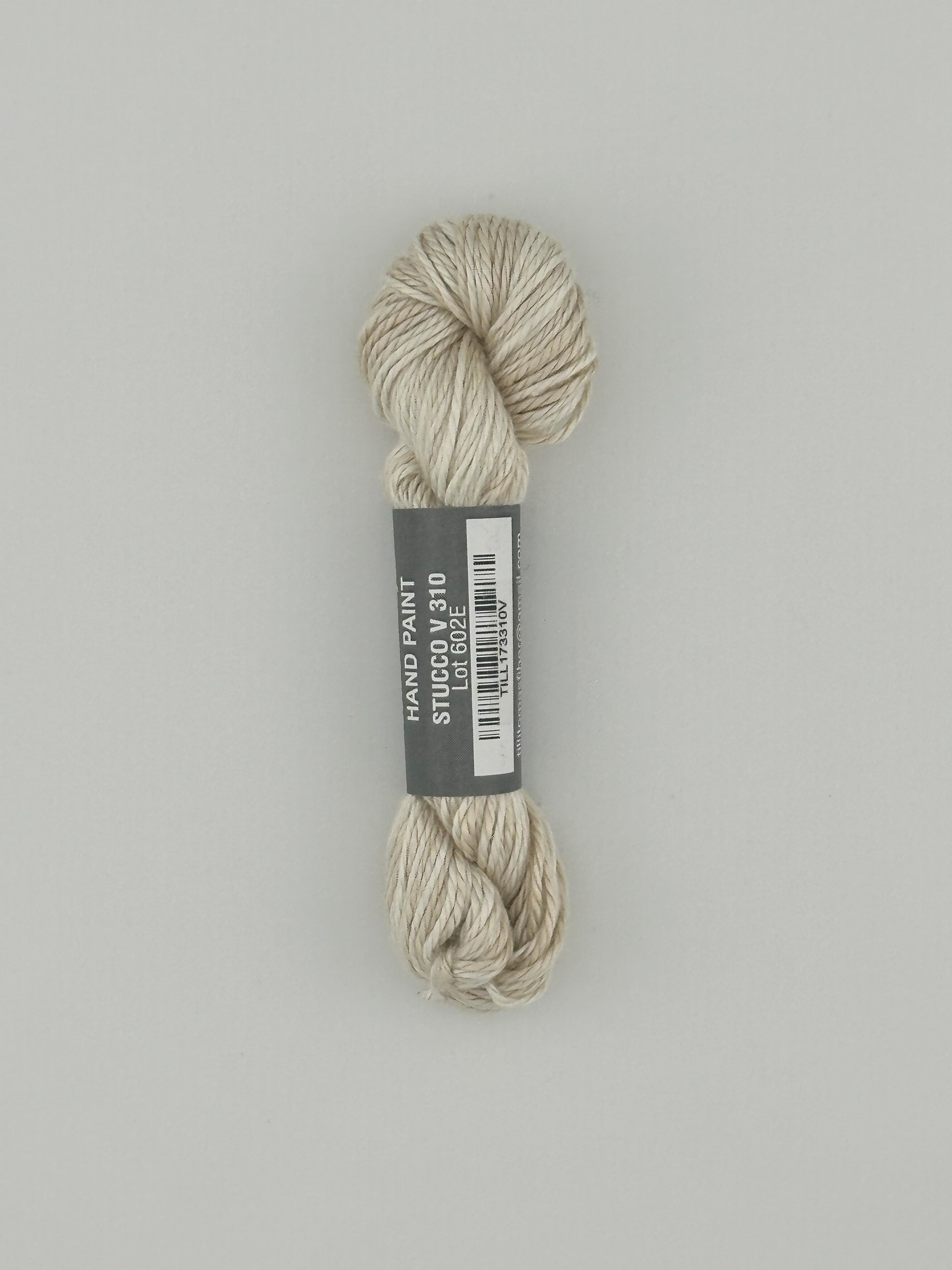 30 yard skein of Pepper Pot Silk  variegated needlepoint thread in stucco v310 with black and white label lying flat on white background