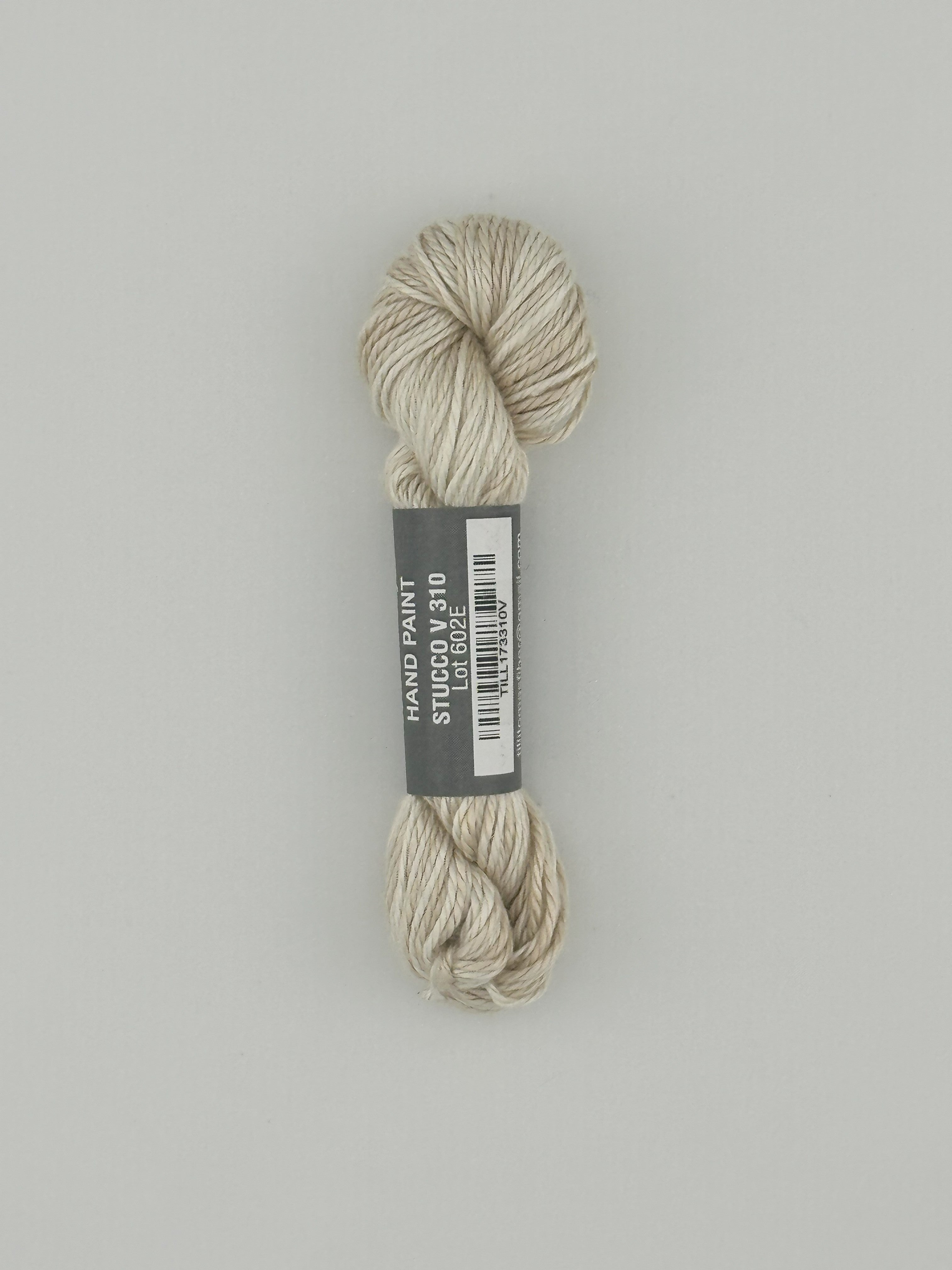 30 yard skein of Pepper Pot Silk  variegated needlepoint thread in stucco v310 with black and white label lying flat on white background