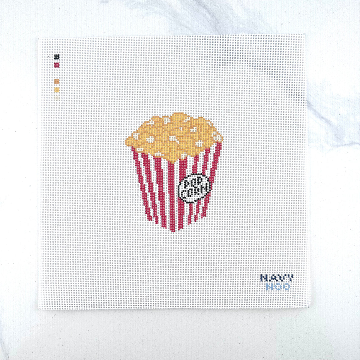 18 mesh needlepoint canvas featuring a red-and-white striped popcorn bucket filled with yellow popcorn, plus a small 'POP CORN' label. The canvas is photographed on a white surface, with the brand name 'NAVY NOO' printed in the bottom right corner.