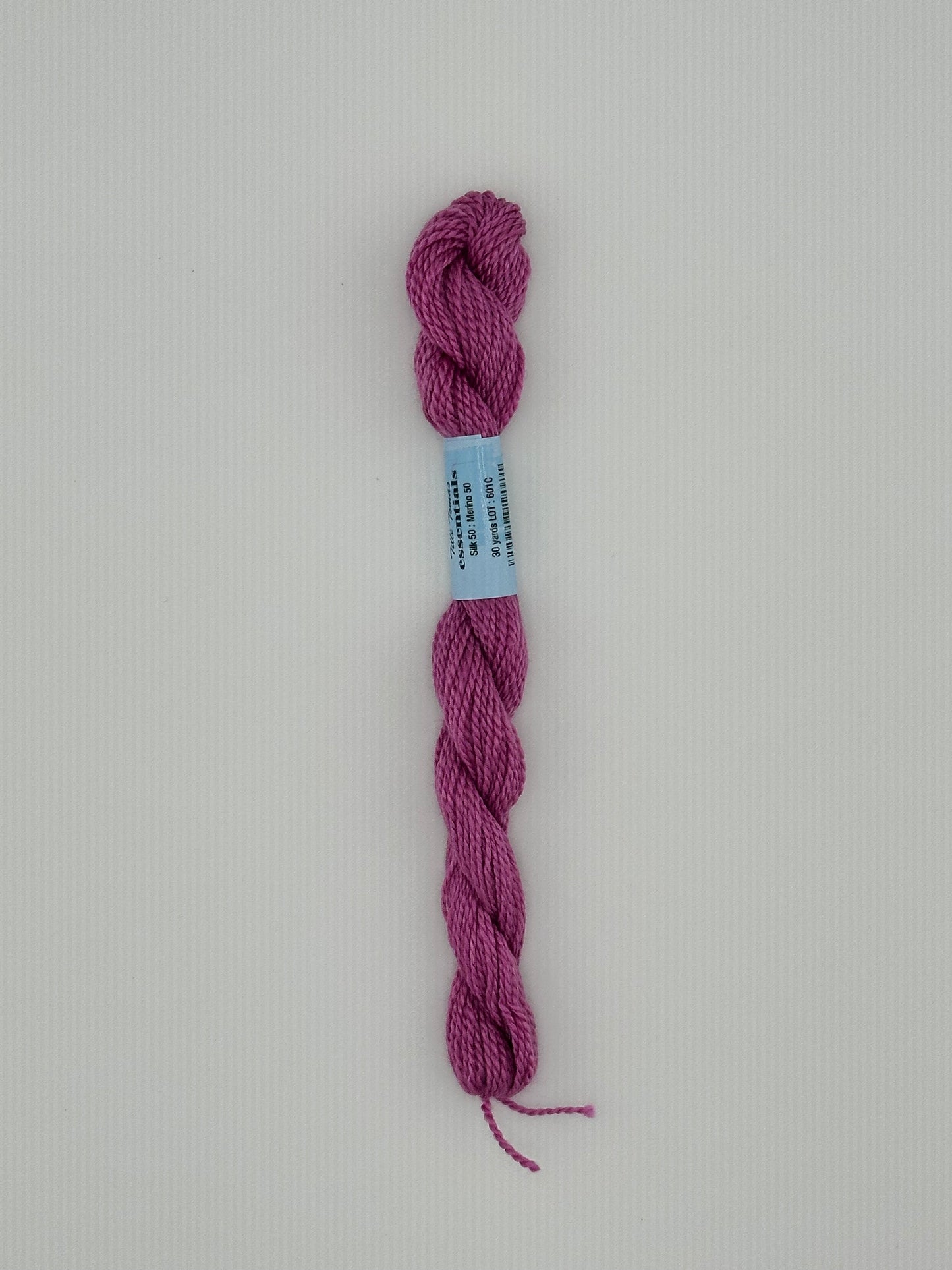 30 yard skein of essentials needlepoint thread in Rocket S7, with blue label lying flat on white background6 pink