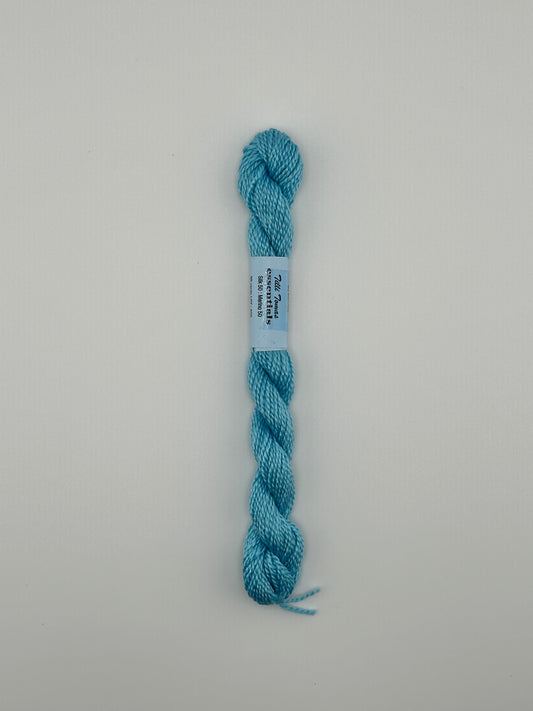 30 yard skein of essentials needlepoint thread in Sprinkler S696 blue, with blue label lying flat on white background