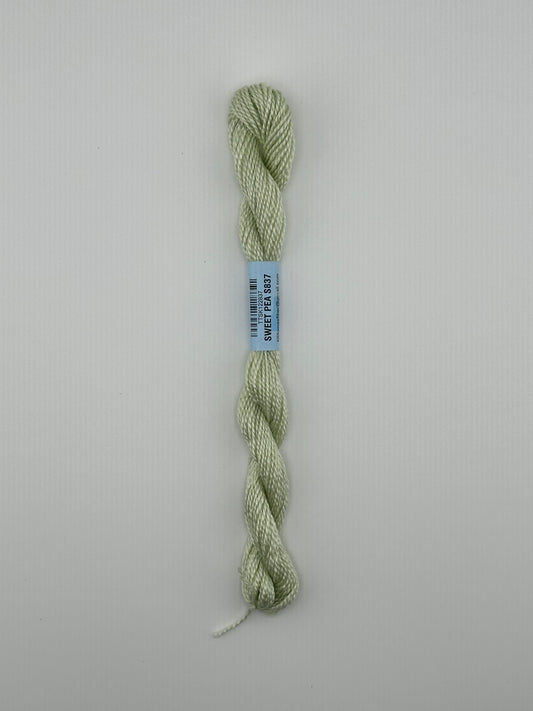 30 yard skein of essentials needlepoint thread in Sweet pea S837 green, with blue label lying flat on white background