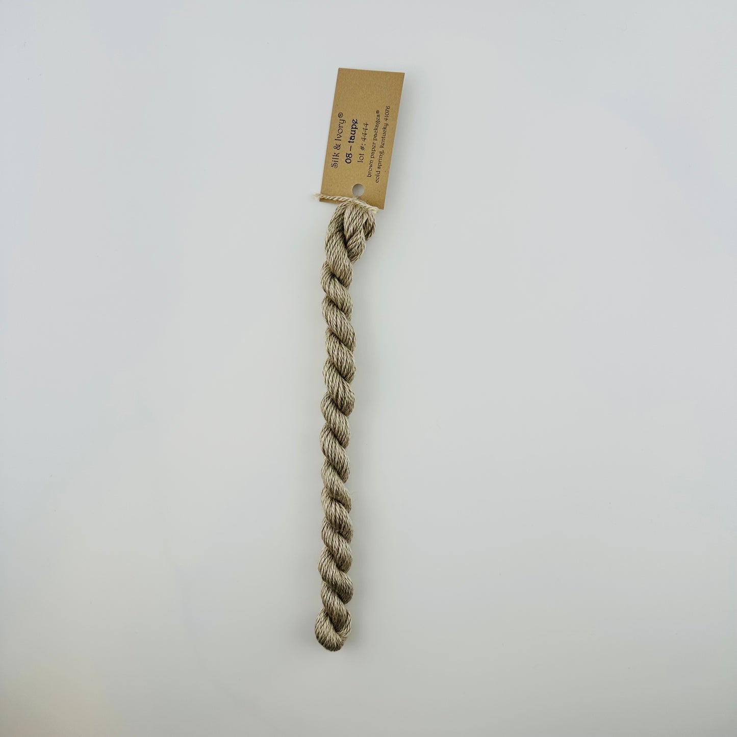 30 yard skein of silk & Ivory in the color 08 Taupe with brown tag laying flat on white background