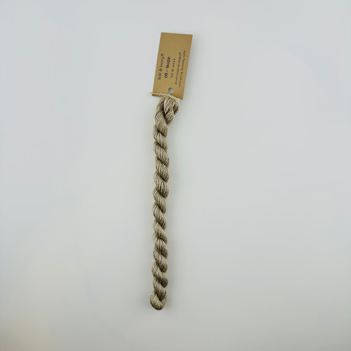 30 yard skein of silk & Ivory in the color 08 Taupe with brown tag laying flat on white background