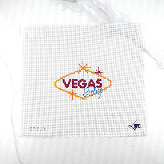 18 mesh needlepoint canvas featuring a 'Vegas Baby' design. The design includes a gold diamond outline, dark red 'VEGAS' text, and blue 'Baby' script, accented with small orange and red starbursts.
