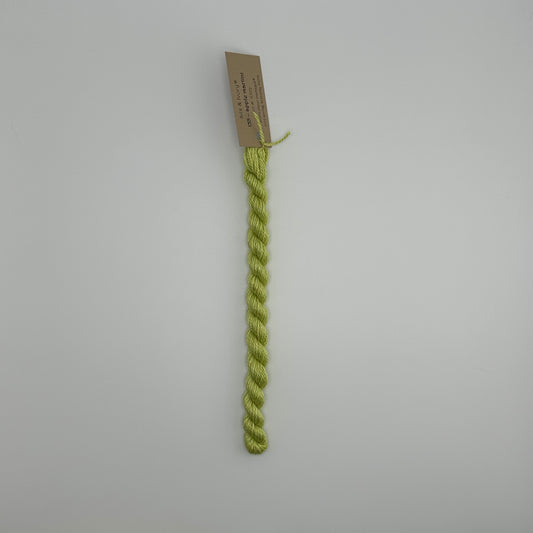 30 yard skein of silk & Ivory in the color 155 Apple Martini with brown tag laying flat on white background