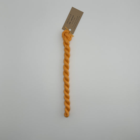30 yard skein of silk & Ivory in the color 138 Apricot with brown tag laying flat on white background