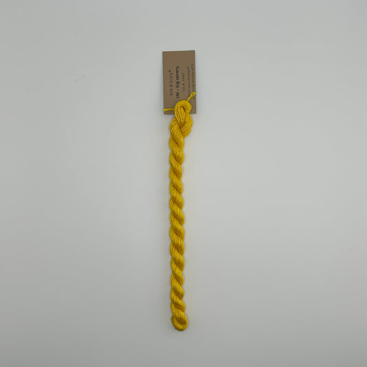 30 yard skein of silk & Ivory in the color 156 Big Canary with brown tag laying flat on white background