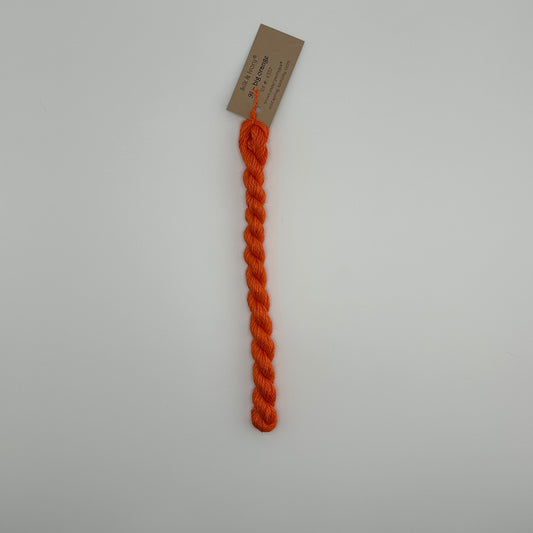 30 yard skein of silk & Ivory in the color 91 Big Orange with brown tag laying flat on white background