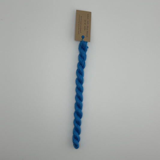 30 yard skein of silk & Ivory in the color 245 Blue Blazes with brown tag laying flat on white background