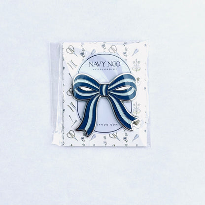 A navy blue and white striped bow magnetic needle holder by Navy Noo, displayed on its branded white backing card inside a clear plastic sleeve, set against a clean white background.