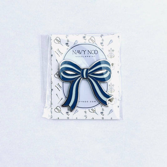 A navy blue and white striped bow magnetic needle holder by Navy Noo, displayed on its branded white backing card inside a clear plastic sleeve, set against a clean white background.