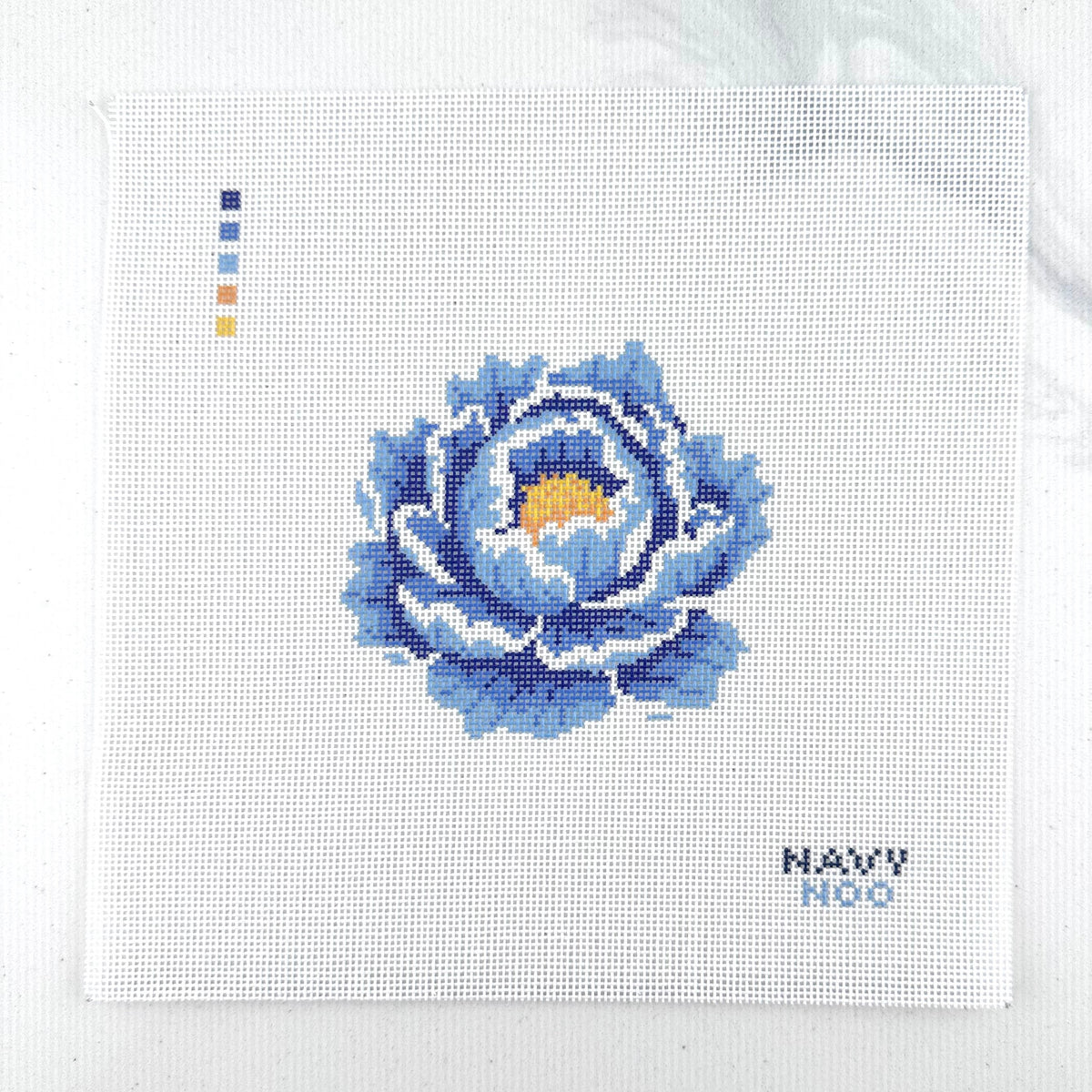 18 mesh needlepoint canvas featuring a blue peony flower with a yellow center, plus small color key squares on the left and the text 'NAVY NOO' on the bottom right, photographed on a white background.