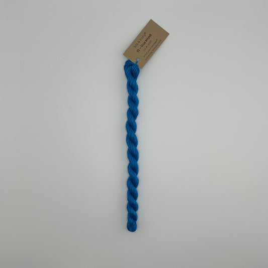 30 yard skein of silk & Ivory in the color 92 Blue Streak with brown tag laying flat on white background