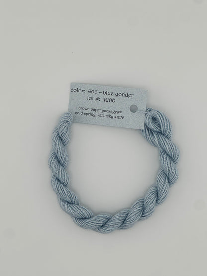 30 yard skein of Stardust Silk and Ivory needlepoint thread in Blue Yonder 606, with light blue label lying flat on white background