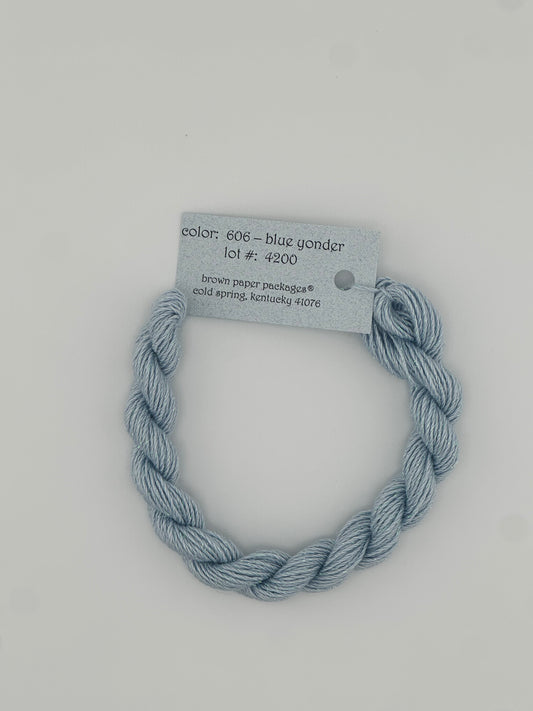 30 yard skein of Stardust Silk and Ivory needlepoint thread in Blue Yonder 606, with light blue label lying flat on white background