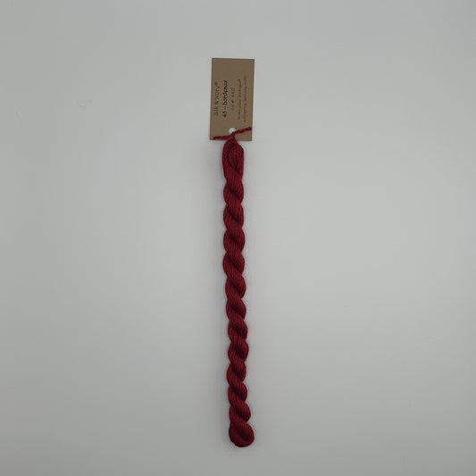 30 yard skein of silk & Ivory in the color 43 Bordeaux with brown tag laying flat on white background