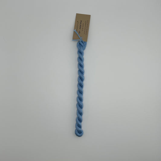 30 yard skein of silk & Ivory in the color 197 Cadet Blue with brown tag laying flat on white background