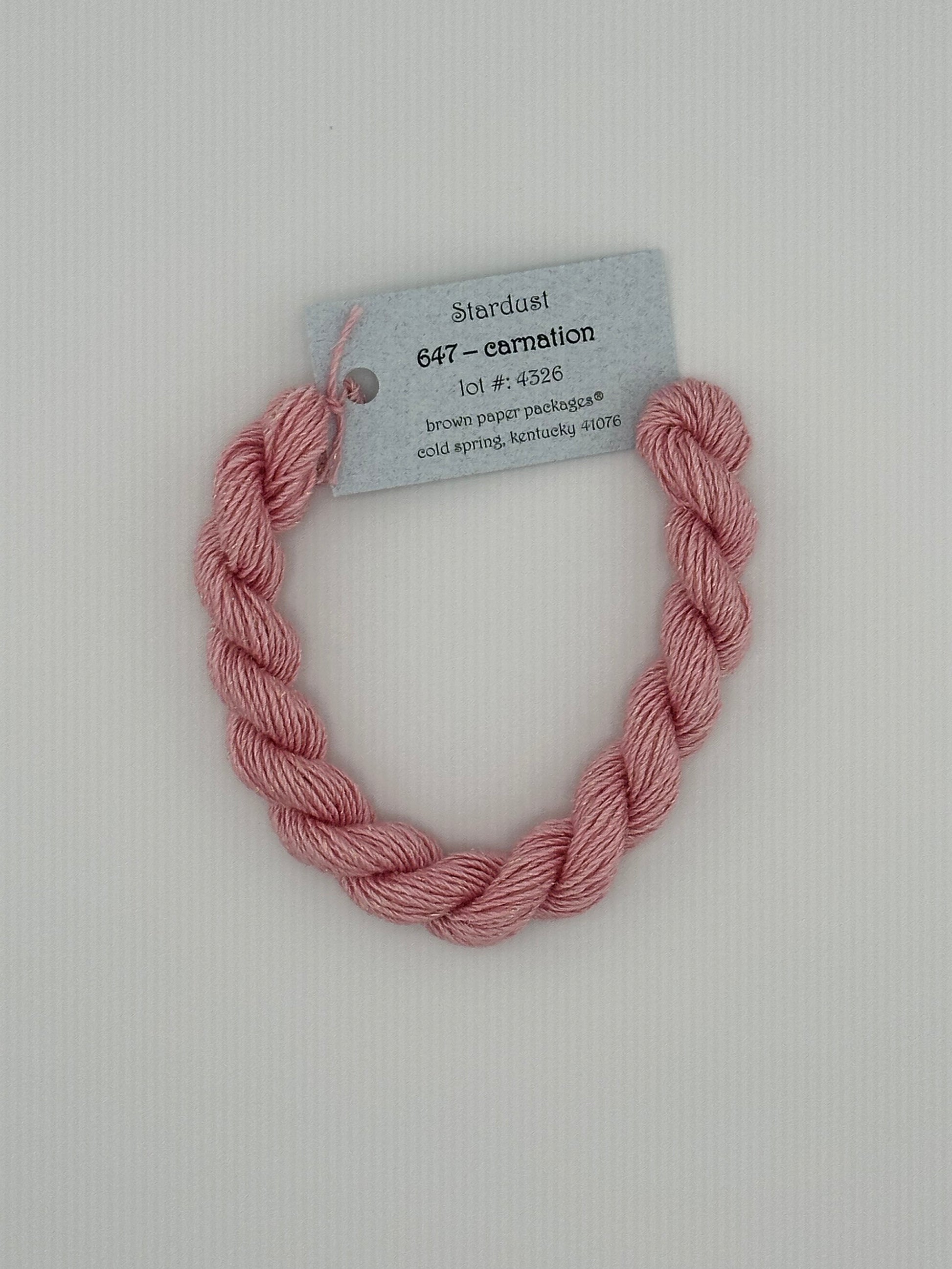 30 yard skein of Stardust Silk and Ivory needlepoint thread in Carnation 647, with light blue label lying flat on white background