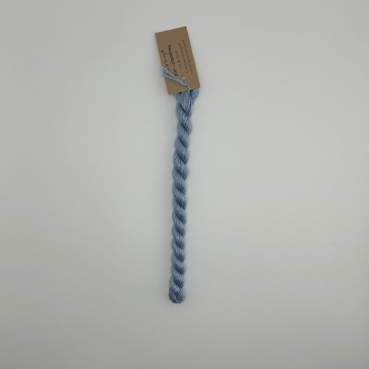 30 yard skein of silk & Ivory in the color 200 Chambray with brown tag laying flat on white background