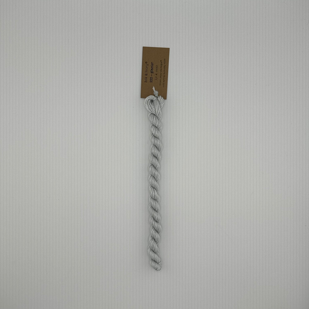 30 yard skein of silk & Ivory in the color 222 Glacier with brown tag laying flat on white background