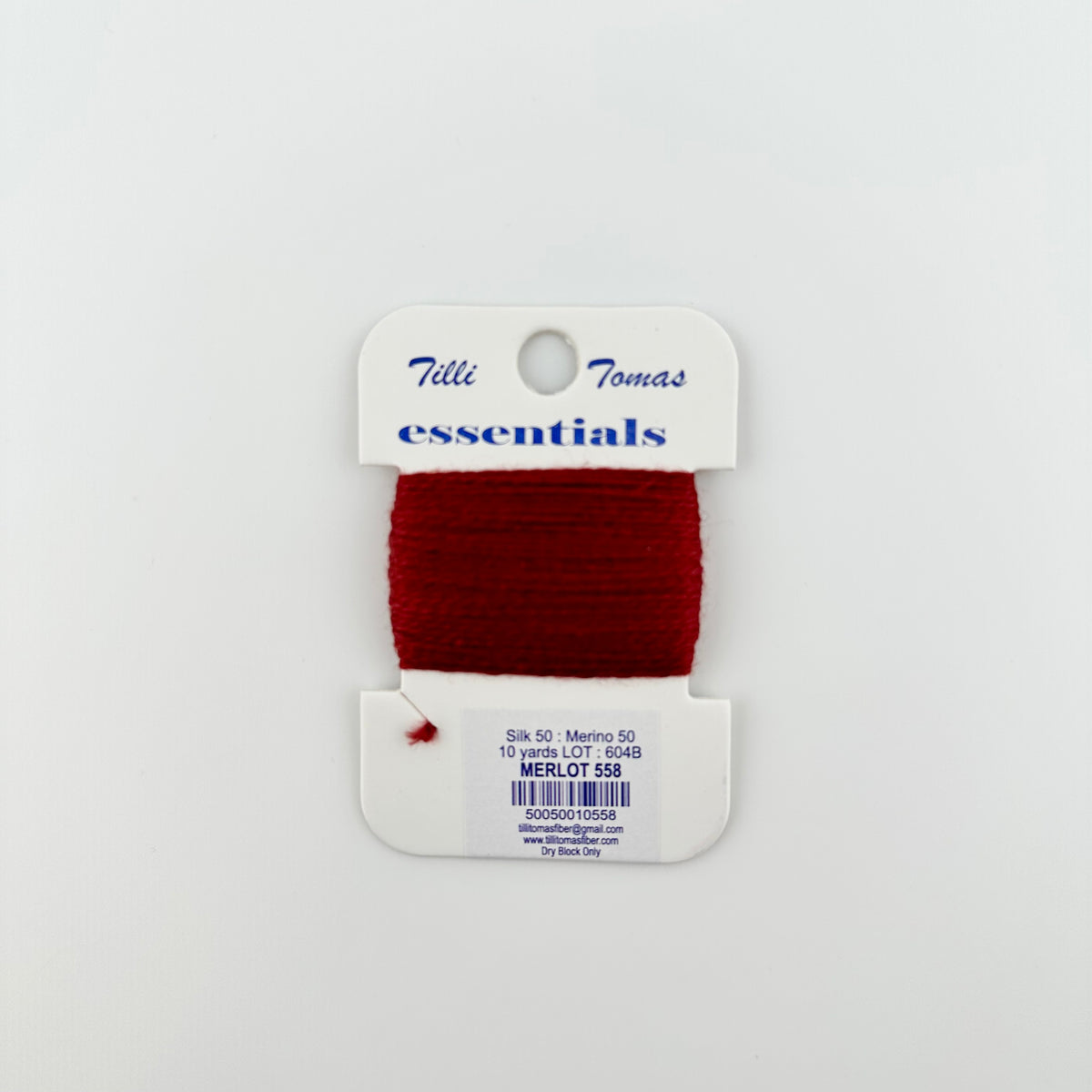 Tilli Tomas Essentials needlepoint thread, in red merlot 558.  50% silk, 50% merino wool, 10 yards wound on a white cardboard card.