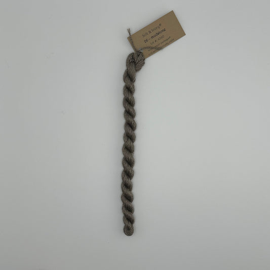 30 yard skein of silk & Ivory in the color 26 Mudstone with brown tag laying flat on white background