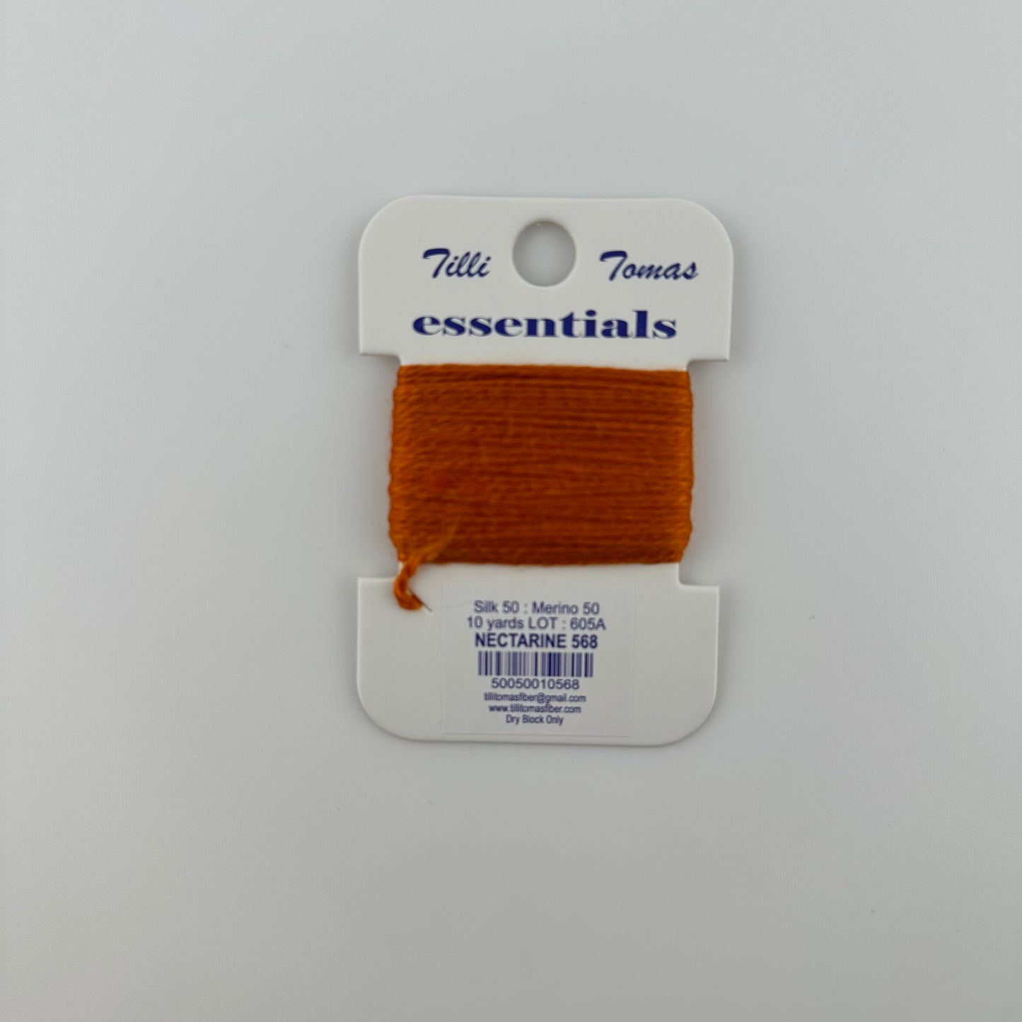 Tilli Tomas Essentials needlepoint thread, in orange nectarine 568.  50% silk, 50% merino wool, 10 yards wound on a white cardboard card.