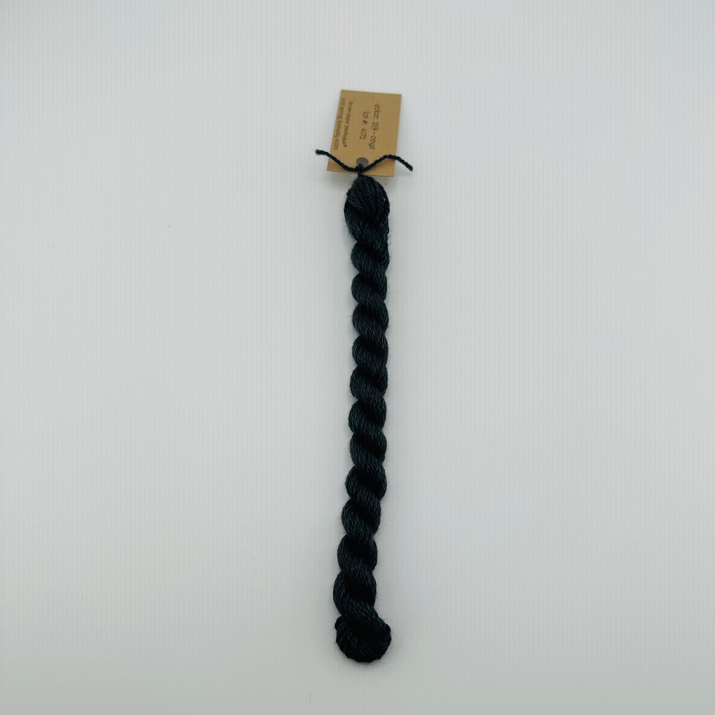 30 yard skein of silk & Ivory in the color 219 Onyx with brown tag laying flat on white background