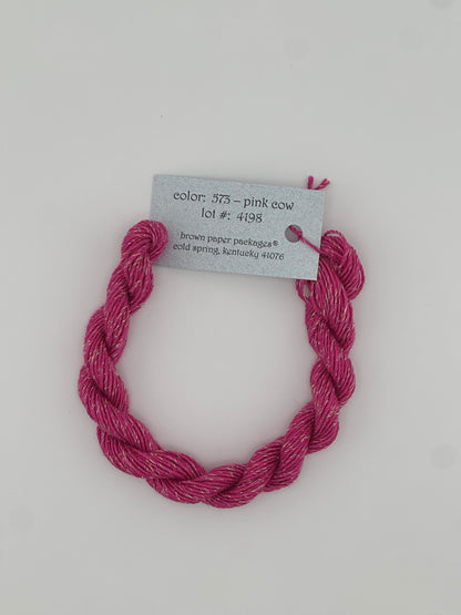 30 yard skein of Stardust Silk and Ivory needlepoint thread in Pink Cow 573, with light blue label lying flat on white background