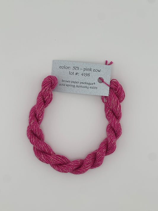30 yard skein of Stardust Silk and Ivory needlepoint thread in Pink Cow 573, with light blue label lying flat on white background