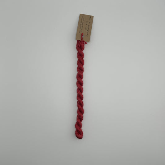 30 yard skein of silk & Ivory in the color 97 Pomegranate with brown tag laying flat on white background