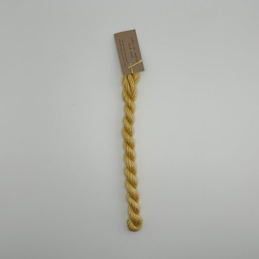30 yard skein of silk & Ivory in the color 121 Saffron with brown tag laying flat on white background