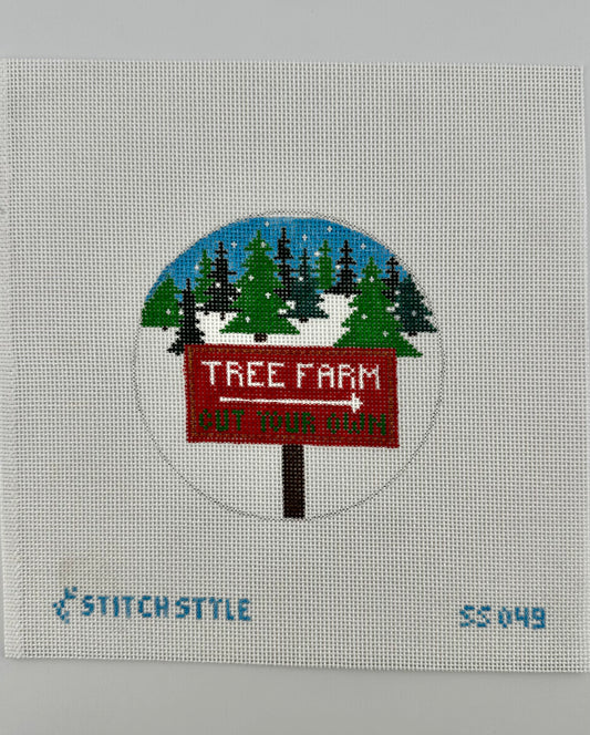 18 mesh needlepoint canvas featuring a design of a red 'Tree Farm' sign with a white arrow pointing right, set against a snowy pine tree landscape under a blue sky. The canvas is displayed on a white background with Stitch-Style branding and product code printed on the bottom.